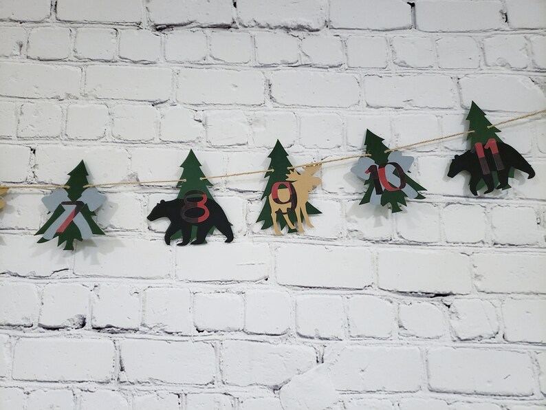 May include: A green and brown woodland-themed banner with cut-out trees, bears, and moose. The banner has the numbers 7, 8, 9, 10, and 11 on it.