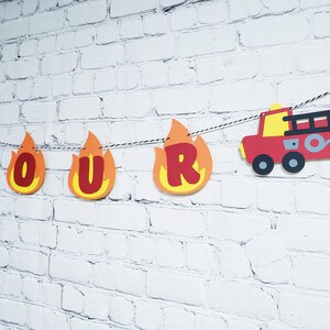 May include: Fire truck themed birthday banner with the word "FOUR" in red letters on orange flames. The banner also includes a red fire truck with black details.