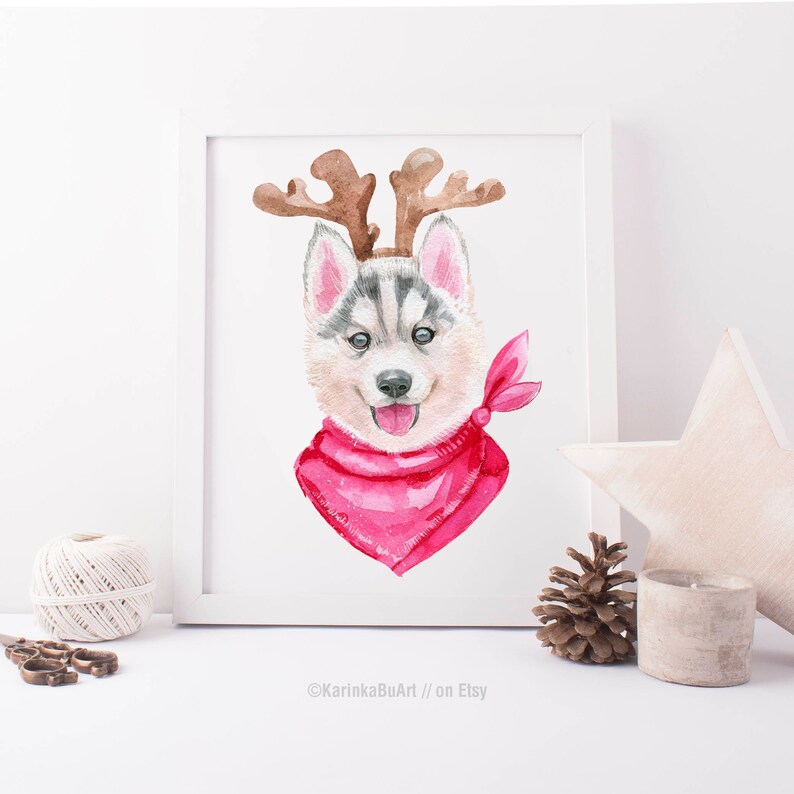 May include: Watercolor painting of a husky puppy wearing a pink bandana and reindeer antlers. The puppy has blue eyes and a pink nose. The background is white.