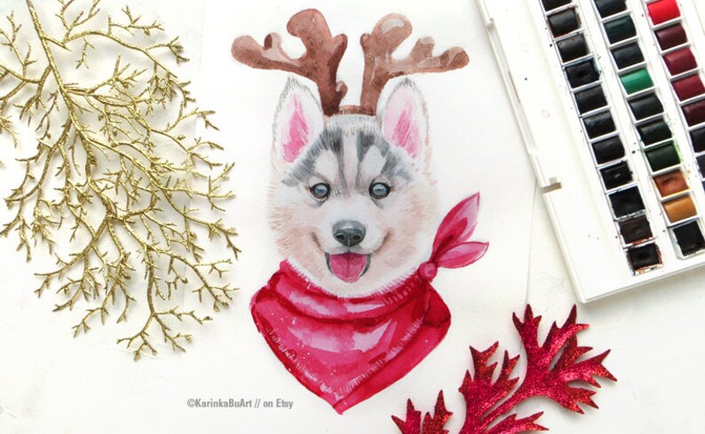 May include: Watercolor painting of a husky puppy wearing a red bandana and reindeer antlers. The puppy has a happy expression and is looking directly at the viewer. The painting is on a white background.