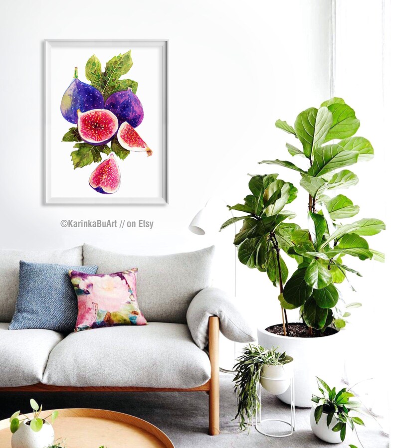 May include: Watercolor painting of a bunch of purple and pink figs with green leaves. The painting is framed and hanging on a white wall in a living room setting.