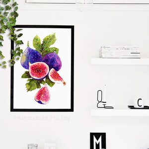 May include: Watercolor painting of a bunch of purple figs with green leaves. The figs are cut open to show the pink flesh inside. The painting is framed in black and displayed on a white wall.