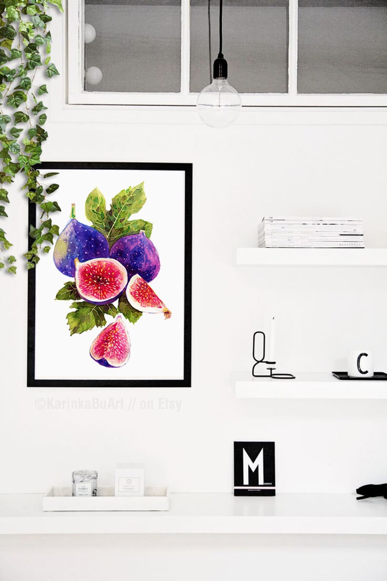 May include: Watercolor painting of a bunch of purple figs with green leaves. The figs are cut open to show the pink flesh inside. The painting is framed in black and displayed on a white wall.