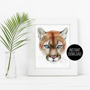 May include: A watercolor painting of a cougar's face with blue eyes. The cougar is looking directly at the viewer. The background is white. The text "INSTANT DOWNLOAD" is in a black circle in the bottom right corner of the image.