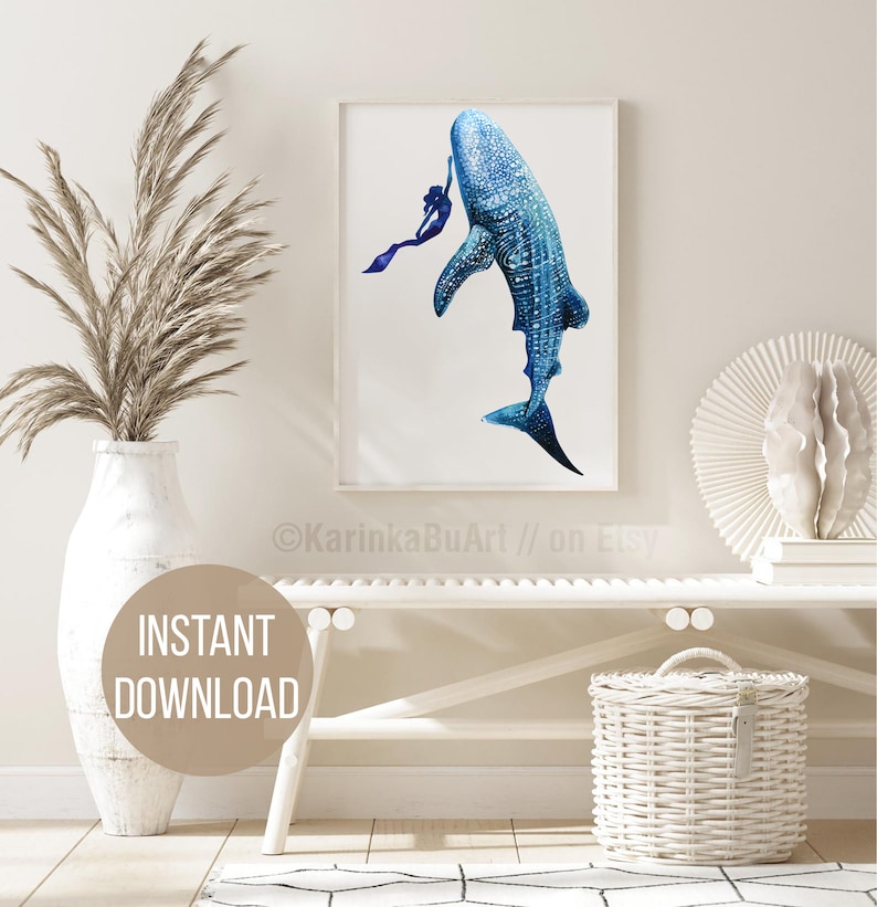 May include: A watercolor painting of a whale shark swimming with a diver. The whale shark is blue and white with black spots. The diver is wearing a purple wetsuit and is holding onto the whale shark's fin. The painting is framed in a white frame and is hanging on a white wall.