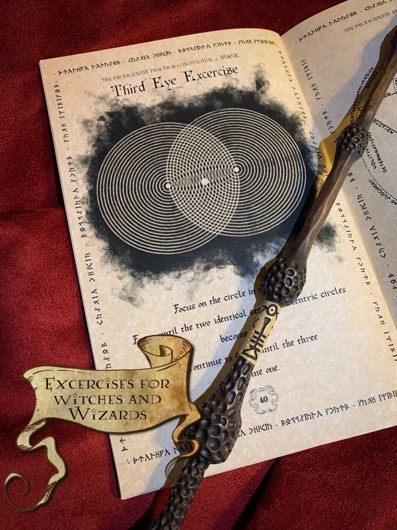 Open parchment-colored book titled Third Eye Exercise with black concentric circles design. A wand rests atop, beside a gold bookmark stating Exercises for Witches and Wizards. Set against a plush red velvet background. Magical study tools.