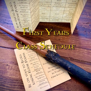 Folded parchment detailing a weekly class schedule for young magical learners. Displayed on a wooden surface, accompanied by a reddish quill and a dark wand with detailed crafting. Bolded text reads First Years Class Schedule.