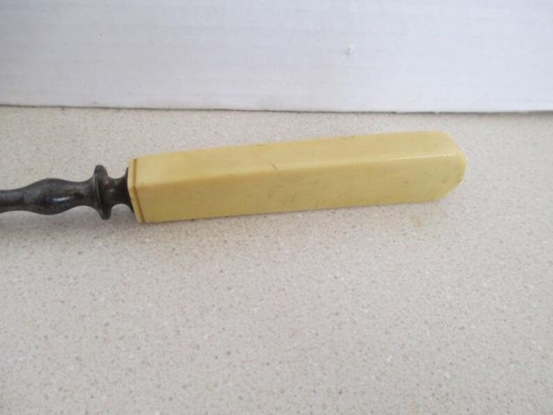Pu&ograve; includere: Un coltello da burro vintage in metallo e avorio con un manico lungo e rettangolare.