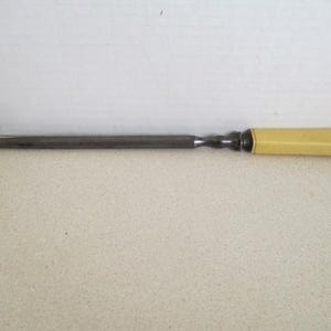 Pu&ograve; includere: Un coltello lungo e sottile in metallo con un manico in plastica gialla. Il coltello &egrave; lungo circa 25 cm.