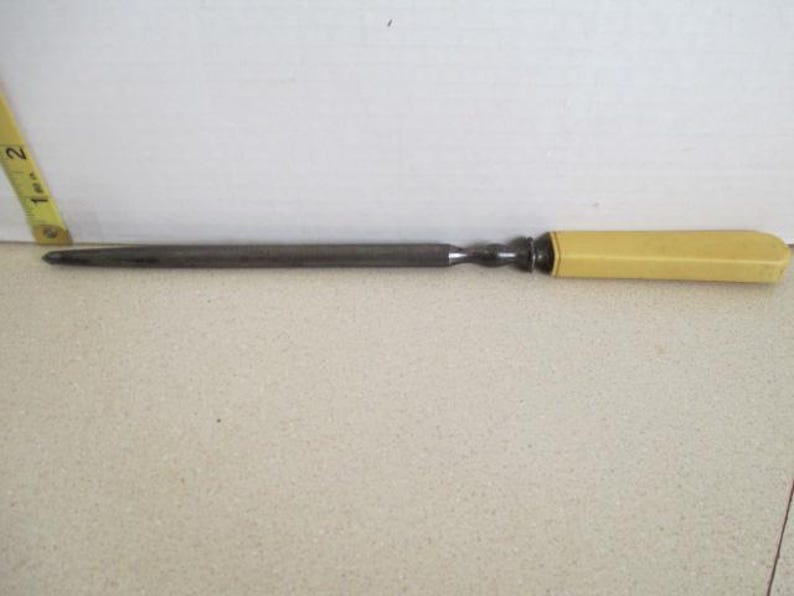 Pu&ograve; includere: Un coltello lungo e sottile in metallo con un manico in plastica gialla. Il coltello &egrave; lungo circa 25 cm.