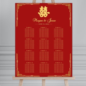 Puede incluir: Plano de asientos de boda rojo con detalles dorados y un símbolo chino de doble felicidad. El gráfico enumera las mesas del 1 al 12 con los nombres de los invitados.
