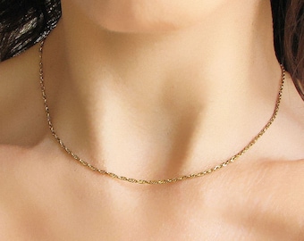 May include: A delicate gold chain necklace on a person's neck. The chain is thin and has a rope-like texture.