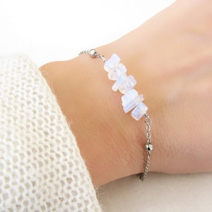 Op de afbeelding: Een delicate zilveren kettingarmband met een rij witte opaal chips. De armband is verstelbaar en heeft aan elk uiteinde een kleine zilveren kraal.
