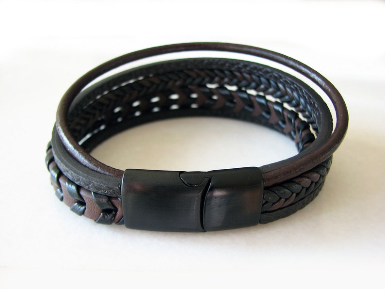 May include: A multi-layered leather bracelet with a black braided leather strap and a black metal clasp.