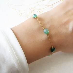 Puede incluir: Un delicado brazalete de cadena dorada con cuentas de &aacute;gata verde. El brazalete est&aacute; en la mu&ntilde;eca de una persona.