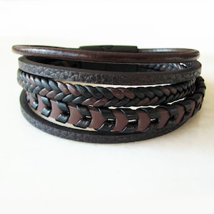 May include: A multi-layered leather bracelet with a braided design in black and brown.