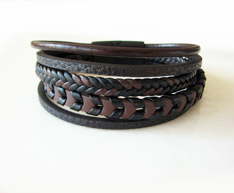 May include: A multi-layered leather bracelet with a braided design in black and brown.