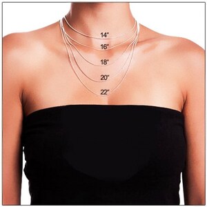 Puede incluir: Una modelo lleva una blusa negra con cinco cadenas plateadas de diferentes longitudes. Las cadenas est&aacute;n etiquetadas con sus longitudes en pulgadas: 14", 16", 18", 20" y 22".