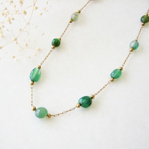 Puede incluir: Un collar de cadena dorada con cuentas de piedras preciosas ovaladas verdes.