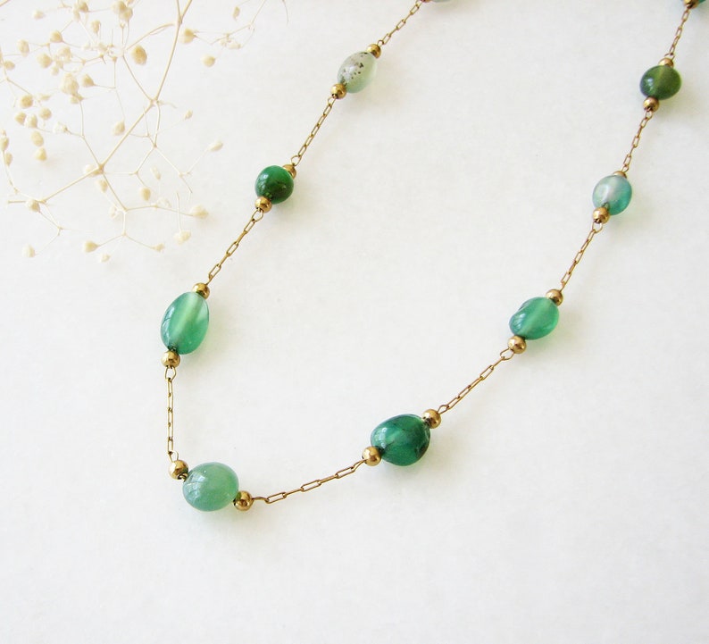 Puede incluir: Un collar de cadena dorada con cuentas de piedras preciosas ovaladas verdes.