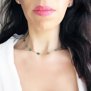 Puede incluir: Un delicado collar de cadena de oro con peque&ntilde;as piedras preciosas verdes de forma ovalada. El collar lo lleva una persona con el pelo largo y oscuro.