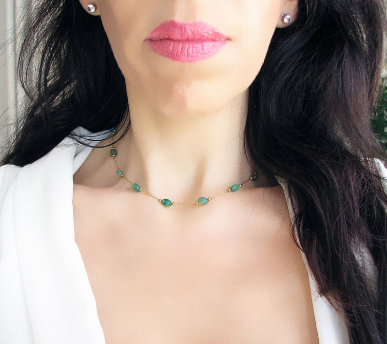 Puede incluir: Un delicado collar de cadena de oro con peque&ntilde;as piedras preciosas verdes de forma ovalada. El collar lo lleva una persona con el pelo largo y oscuro.