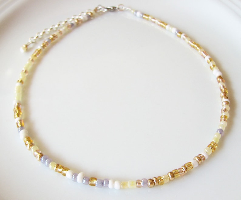 Dainty mix gold seed bead choker necklace made of 2.9mm glass seed beads. Length is 13 inches or 15 inches plus 2 inches extender chain. Closes with stainless steel lobster clasp.