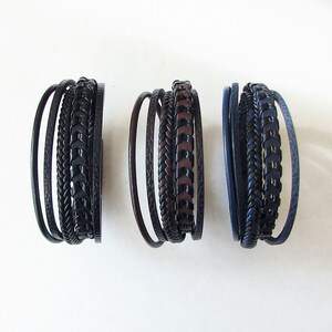May include: Three leather bracelets with different patterns and colors. The bracelets are made of braided leather and have a dark brown, black, and navy blue color scheme.