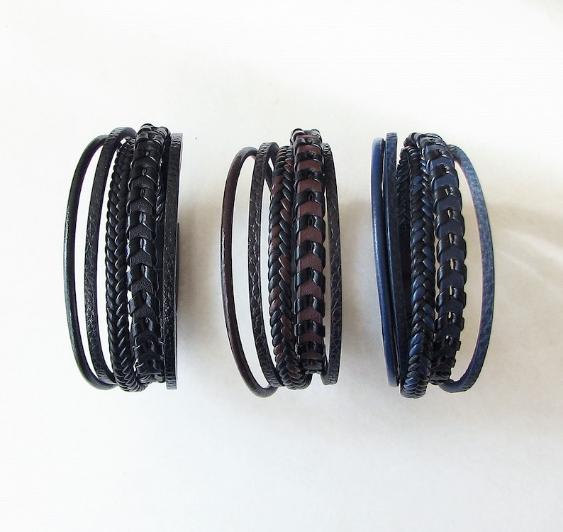 May include: Three leather bracelets with different patterns and colors. The bracelets are made of braided leather and have a dark brown, black, and navy blue color scheme.
