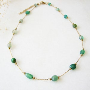 Puede incluir: Un collar de cadena dorada con cuentas de piedras preciosas verdes. El collar es delicado y presenta una variedad de tonos verdes.