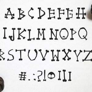 May include: Black and white alphabet with bone-shaped letters. The letters are stylized to look like bones. The alphabet includes all 26 letters, as well as the symbols #, ., ;, ?, !, and a skull and crossbones.