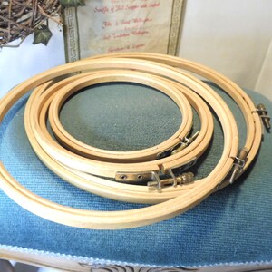 Könnte beinhalten: Satz mit vier Holz-Stickrahmen, ineinander verschachtelt. Die Rahmen sind aus Naturholz und haben eine hellbraune Farbe. Die Rahmen werden verwendet, um Stoff zum Sticken zu spannen.