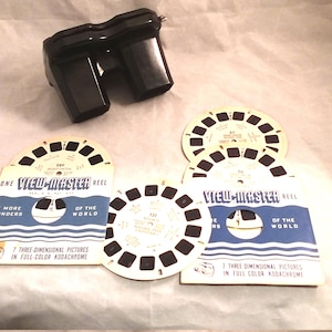 May include: A black plastic View-Master viewer with four reels. The reels are labeled "View-Master Reel" and feature images of "Wonders of the World" in full color Kodachrome.