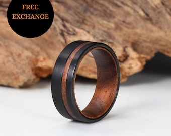 May include: A black tungsten carbide ring with a brown wood inlay. The ring has a polished finish and a beveled edge.