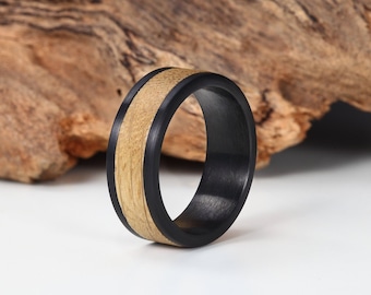 May include: A black and wood ring with a wide band. The ring has a black outer band and a wood inner band.
