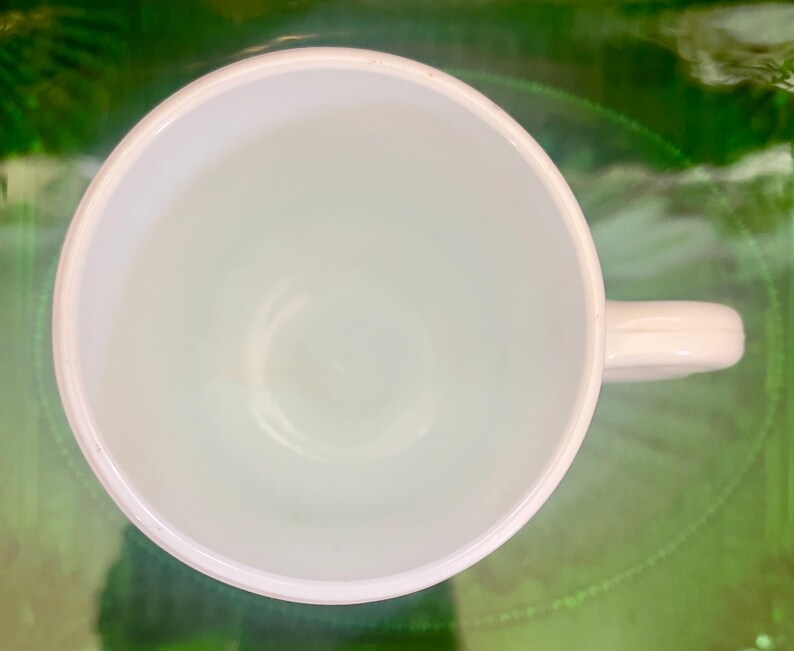 Op de afbeelding: Een witte keramische mok met een handvat. De mok is leeg en heeft een gladde, glanzende afwerking.