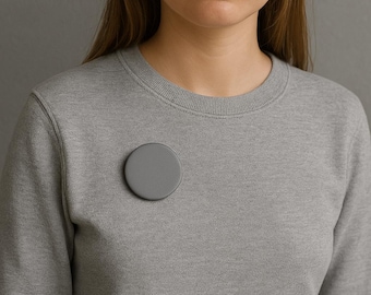 Peut inclure: Un sweat-shirt gris avec une épingle ronde grise sur le devant.