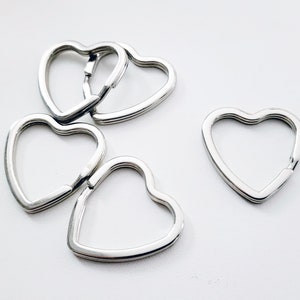 May include: Five silver heart-shaped keychains, with one keychain separated from the group of four.