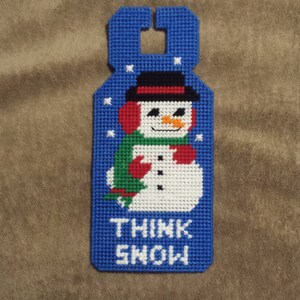 May include: Blue and white door hanger with a snowman design and the text "Think Snow".