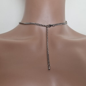 May include: A silver chain necklace with a lobster clasp closure. The chain is adjustable and has a drop-shaped pendant at the end.