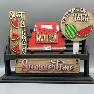 May include: A wooden tiered stand with a red truck cutout, watermelon slices, and signs that say "Sweet Watermelon", "Watermelon Patch", and "Farm Fresh Summertime".