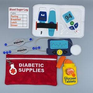 May include: A red felt pouch with a zipper and a white zipper pull. The pouch has the words "DIABETIC SUPPLIES" embroidered on it. There is a white circle with a red cross on it attached to the zipper pull. There are also several other items in the image, including a blood sugar monitor, a glucose meter, and a bottle of glucose tablets.