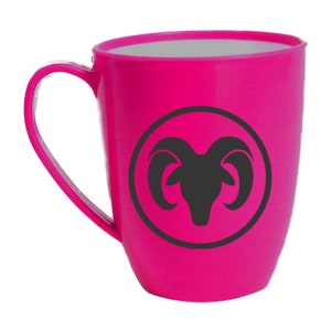 May include: A pink ceramic mug with a black silhouette of an Aries zodiac sign inside a circle.