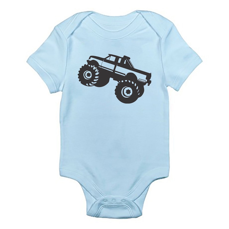 May include: A light blue baby growsuit with a black silhouette of a monster truck.