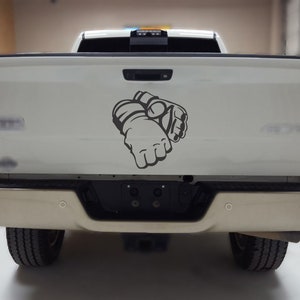May include: A white pickup truck with a gray graphic of a pair of boxing gloves on the tailgate.