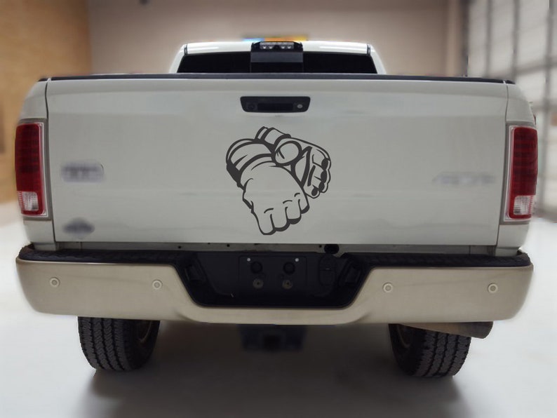 May include: A white pickup truck with a gray graphic of a pair of boxing gloves on the tailgate.