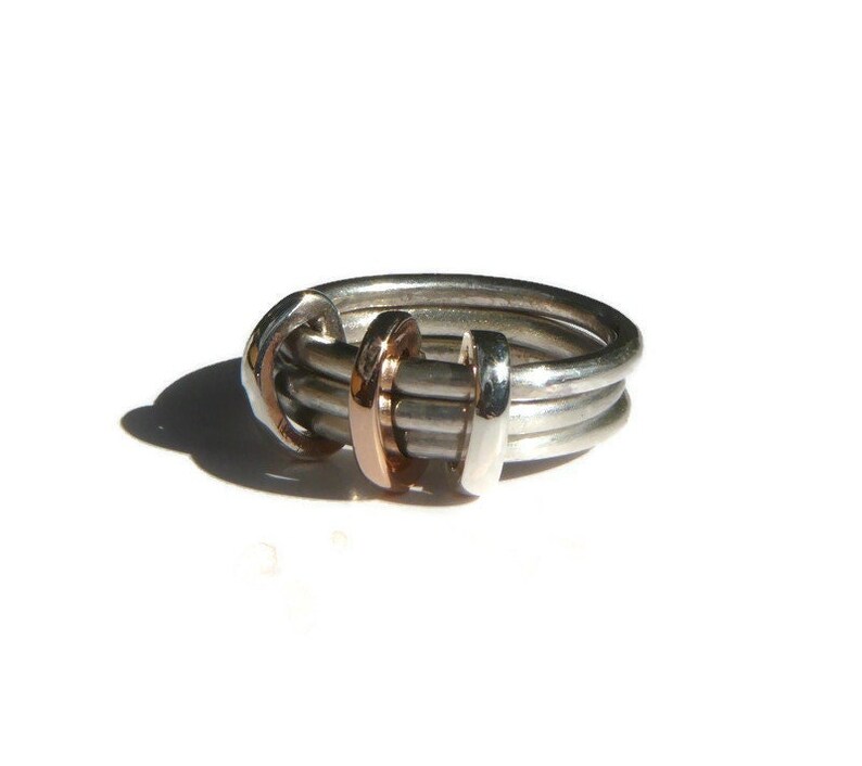 May include: A silver ring with three bands, one of which is rose gold. The bands are intertwined and the ring is polished.