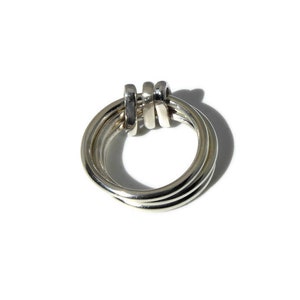 May include: A silver ring with three interlocking bands.