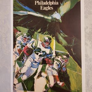 May include: A vintage Philadelphia Eagles poster featuring a stylized illustration of football players in action. The poster has the team name at the top and a green, white, and black color scheme.