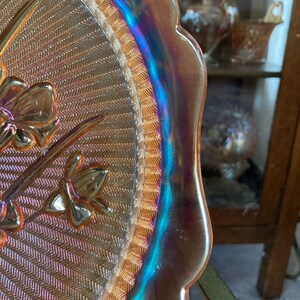 Peut inclure: Une assiette de service en verre iris&eacute; vintage avec un bord festonn&eacute; et un motif tiss&eacute;. L'assiette pr&eacute;sente un motif floral avec une bordure dor&eacute;e.